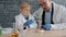 Curious kid holding glass tube heating substance watching reaction in lab with teacher