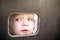 Curious kid spying through the hole in the wooden wall on playground