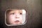 Curious kid spying through the hole in the wooden wall on playground