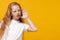 Curious little ginger kid girl 12-13 years old in white t-shirt isolated on yellow background children portrait