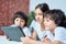 Curious little latin boy looking at the screen of tablet pc. Brother spending time with his siblings, playing games