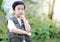 Curious little young Asian boy standing in the garden and touch his chin. Exploring the world, outdoors activity