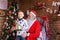 Curious male child receives gift from Santa Claus in decorated f