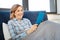 Curious senior woman sitting alone in bed and looking on screen