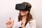 Curious, smiling woman in a white shirt, wearing Oculus Rift VR Virtual reality 3D headset, exploring and touching something