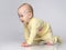 Curious Toddler infant kid crawling on a gray studio background, he dressed with yellow children& x27;s cotton overalls with