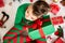 Curious young boy wearing xmas pajamas sitting on the floor on christmas day, shaking his christmas present to hear what is inside