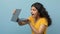 Curious young hindu woman opening laptop, blue background