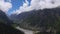 Curling clouds above high mountains and river valley 4K pan time lapse