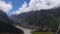 Curling clouds above high mountains and river valley 4K time lapse