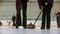 Curling training indoors - leading granite stone on the ice - two women rubbing the ice before the stone