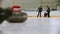 Curling training indoors - leading granite stone on the ice - two young women rubbing the ice before the stone