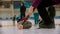 Curling training - woman holding a granite stone with red handle and holding a special brush in another hand