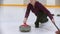 Curling training - a young woman pushes off from the stand with a stone biter