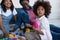 curly african american girl holding building block near mom and grandma smiling on blurred background,stock image