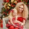 Curly beautiful young blond woman in a red dress embraces daughter in Christmas