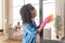 Curly caregiver cleaning the glass door at home of patient