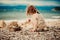 Curly child girl building stone tower on the beach