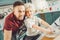 Curly cute boy kneading dough for pie with parental guidance