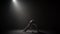 Curly female practicing capoeira in darkness against spotlight in studio.