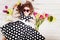 Curly girl with bouquet of tulips lying on white wooden floor.