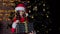 Curly girl in Christmas costume holds a gift near Christmas tree