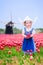 Curly girl in Dutch costume in tulips field with windmill