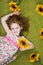 Curly girl with sunflower in grass carpet.