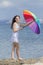 Curly girl in white sleeveless dress closes rainbow umbrella