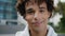 Curly guy face posing city portrait. Young man looking camera smiling on street