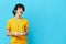 curly guy plays with joystick in yellow t-shirts blue background