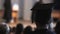 Curly hair man in mortarboard and academic dress looking at stage, graduation