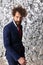 Curly hair man in navy blue suit with long beard posing in a cool manner