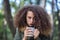 Curly hair teen girl holding mug in the park