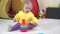 Curly haired baby girl playing with colorful child pyramid.