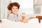 Curly-haired boy sitting backwards on white sofa