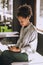 Curly-haired woman sitting on the table with a phone in hands