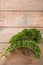 Curly leaves of kale or green leaf cabbage on rustic wooden planks, vertical format with large copy space for an announcement