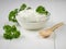 Curly leaves of parsley and a bowl of curd cream and spoon on a white table.