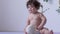 Curly little girl eats cookie and waving plump hands on photosession in studio