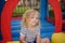 Curly little girl having fun in leisure center for kids. Child sport activity on outdoor playground. Toddler girl playing in