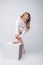 Curly little girl tying pointe, on gray backdrop