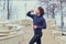 Curly Male runner drinks water from a bottle in park on the stai