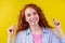 Curly redhead caucasian woman use ears sticks in studio yellow background