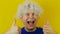 Curly screaming man with white hair, thumbs up, funny and cheerfully human emotion, on yellow wall background