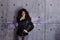 Curly woman actively posing on concrete wall background. Colored illuminated inscription is projected onto the wall.