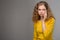 Curly young woman in yellow clothes displeased looking at hair o