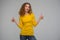 Curly young woman in yellow clothes displeased looking at hair o