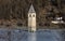 CURON VENOSTA, 06 January 2023: Tourists walk on the frozen lake of Resia. It is an artificial reservoir in the west of South