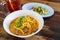 Curried noodle soup Khao soi with beef and spicy coconut milk on wood table.